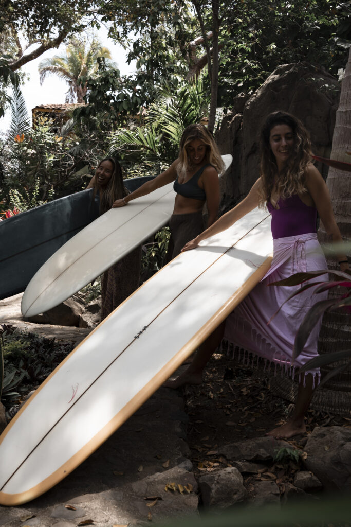 Surfing girls hold their longboards